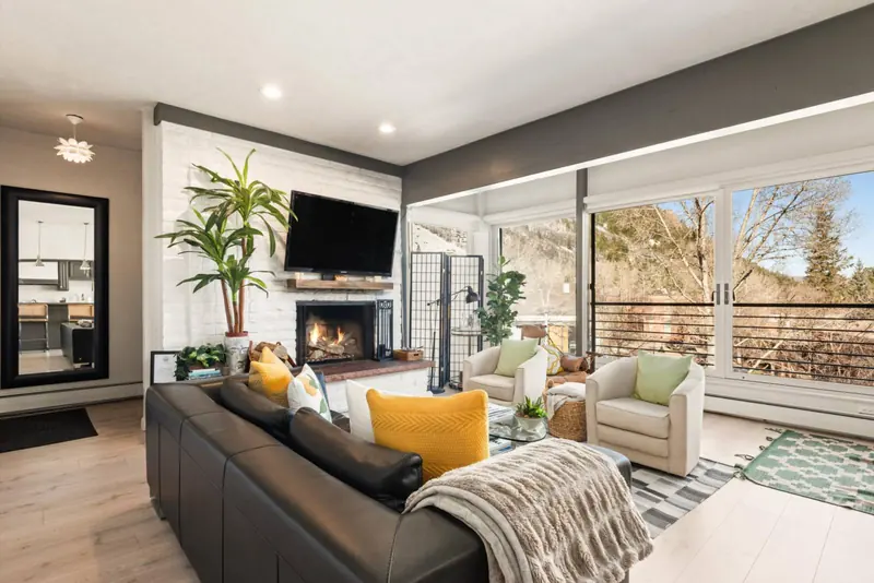The living room is very inviting with a large flat screen TV, wood burning fireplace and wall to wall windows with amazing views.